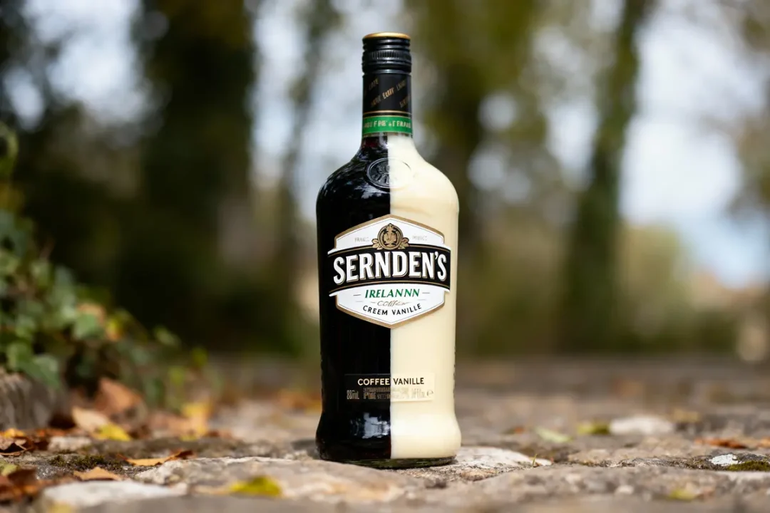 Bouteille de liqueur Sernden's Coffee Vanilla sur un chemin pavé extérieur, entourée de feuilles.