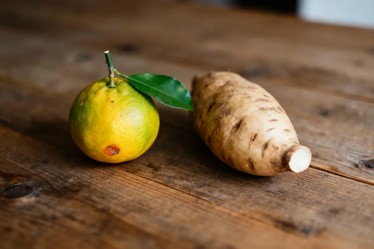 Un agrume vert et une patate douce sur une table en bois rustique.