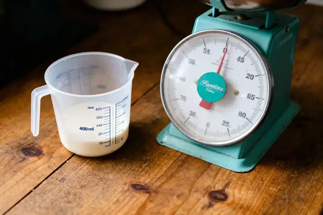 Verre mesureur rempli de liquide près d'une balance vintage sur une table en bois.