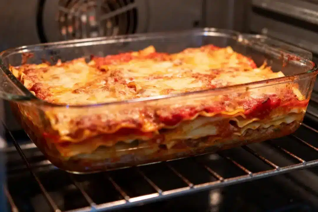 Plat de lasagnes appétissantes dans un four, avec fromage gratiné et sauce tomate.