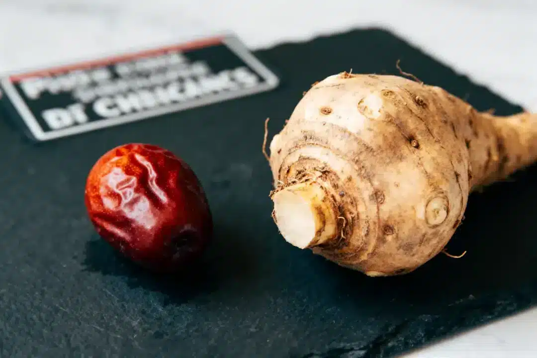 Une racine de manioc et une datte rouge sur une ardoise noire.