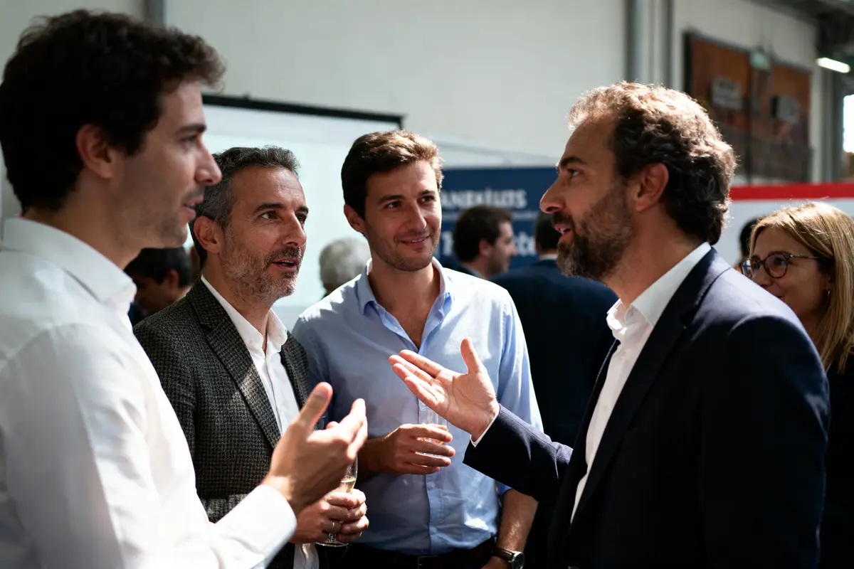 Quatre personnes en discussion lors d'un événement professionnel, tenues élégantes, intérieur bien éclairé.