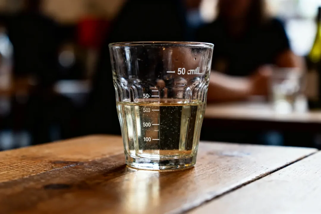 Verre rempli de liquide jusqu'à 50 centilitros sur une table en bois dans un café