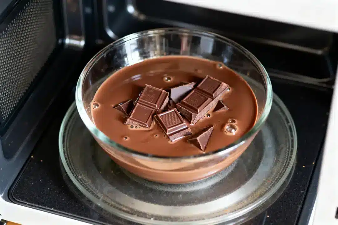 Bol de chocolat fondu au micro-ondes avec morceaux fondants dans un récipient en verre