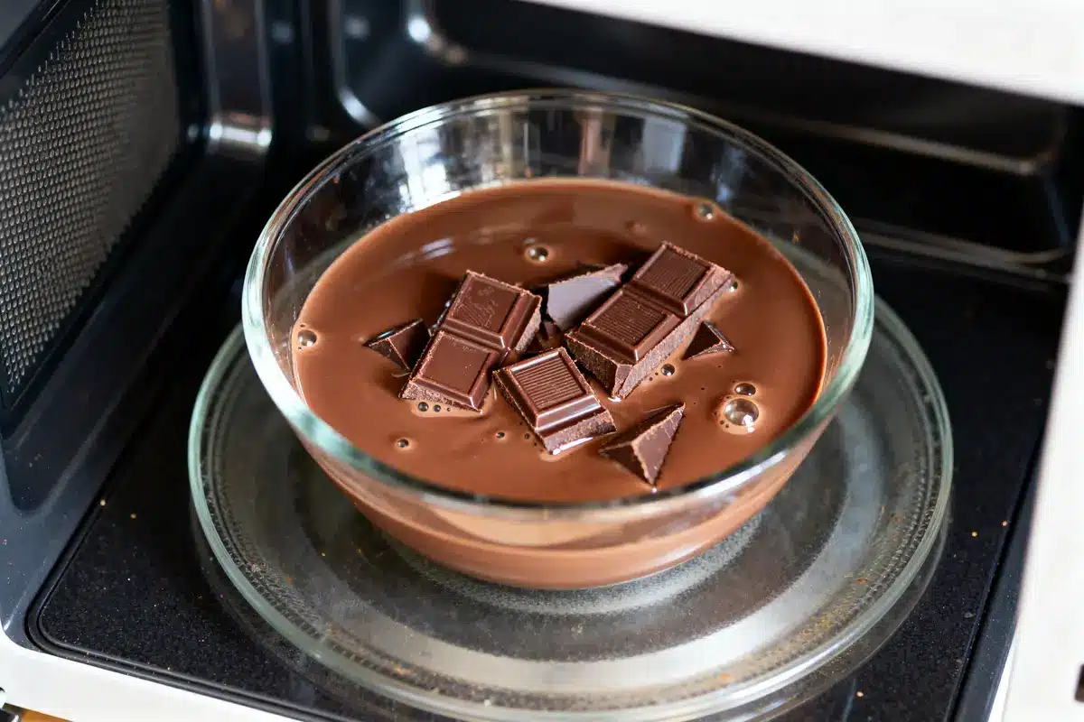 Bol de chocolat fondu au micro-ondes avec morceaux fondants dans un récipient en verre