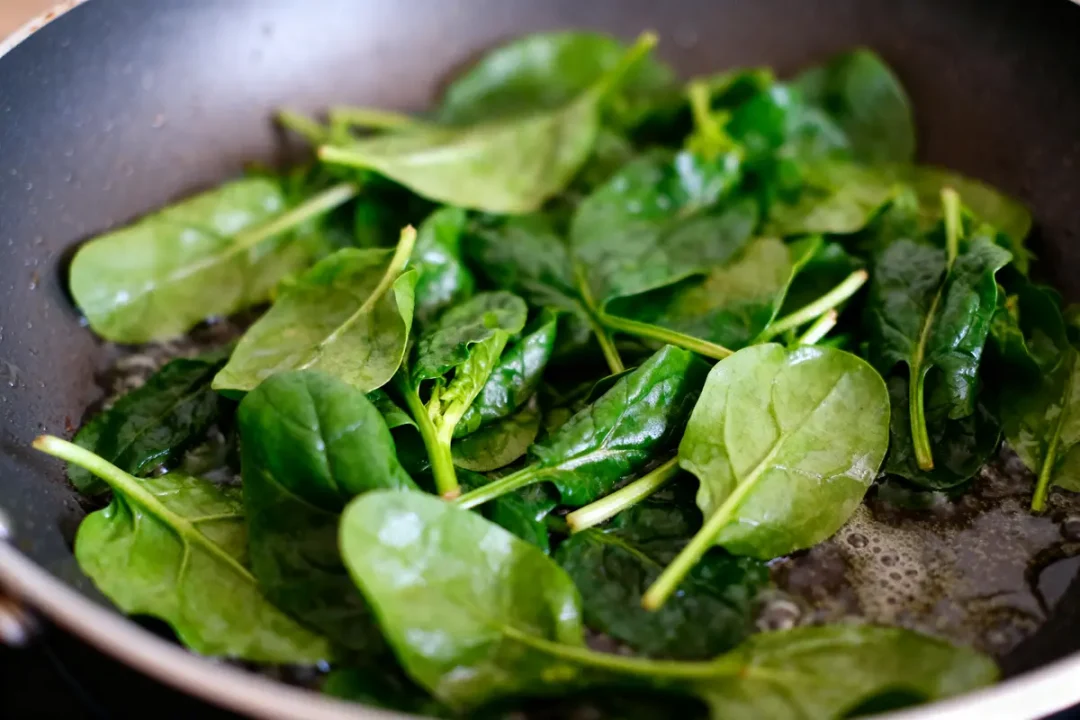 Feuilles d'épinards fraîches en cuisson douce dans une poêle chaude