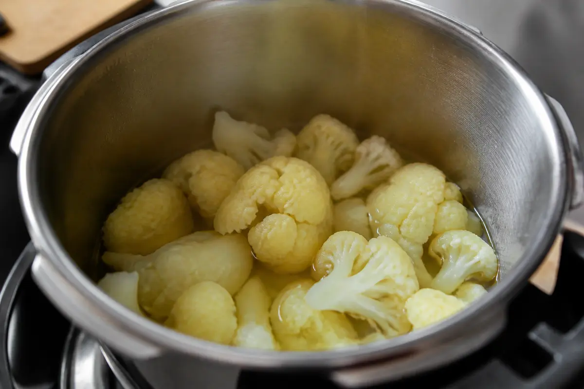 Fleurs de chou-fleur en cuisson à la cocotte-minute sur une cuisinière noire