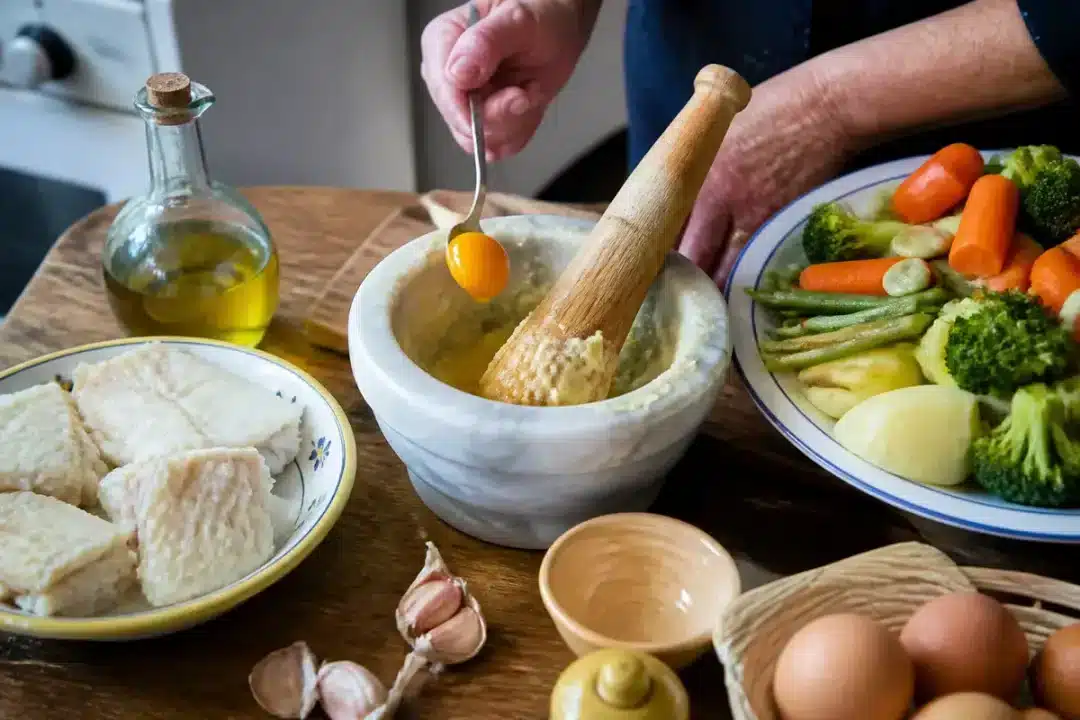Préparation traditionnelle de la recette d'aïoli grand-mère avec ingrédients frais et mortier en marbre