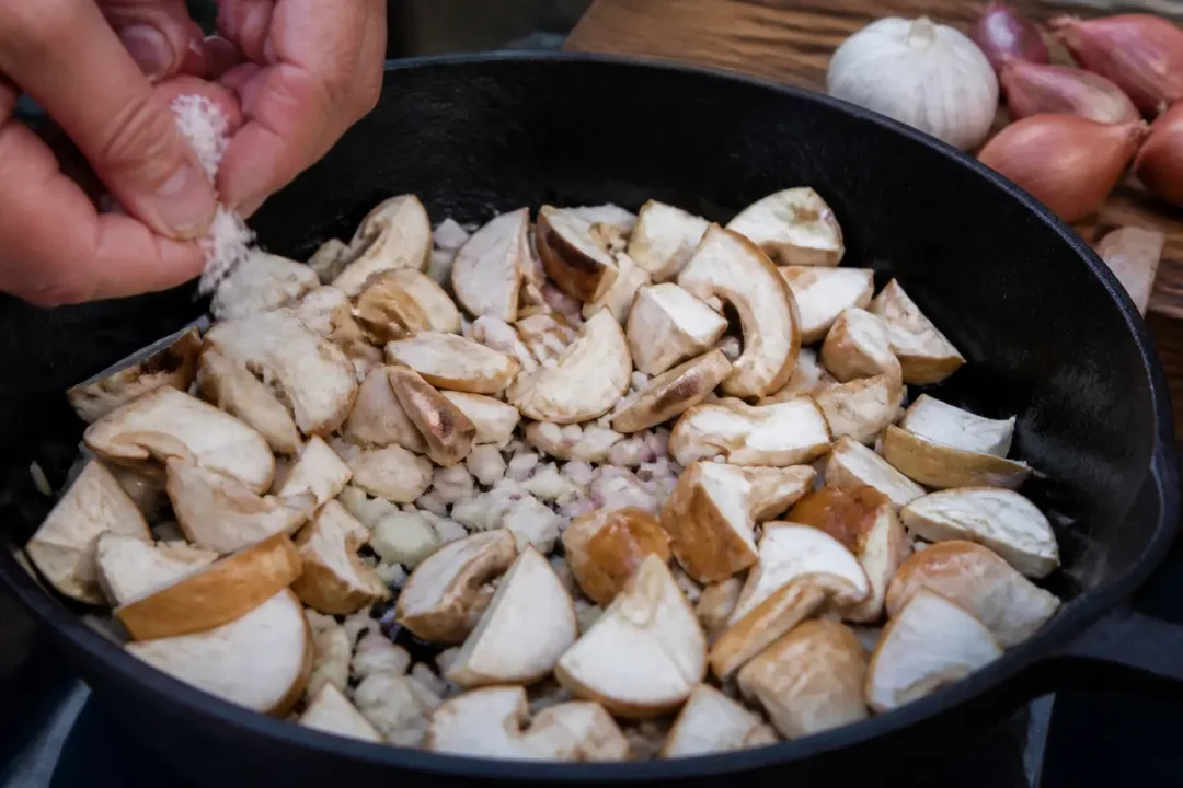 Cuisson de champignons pour recette de pied-de-mouton avec ail et échalotes émincées