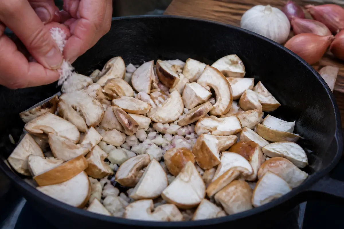 Cuisson de champignons pour recette de pied-de-mouton avec ail et échalotes émincées
