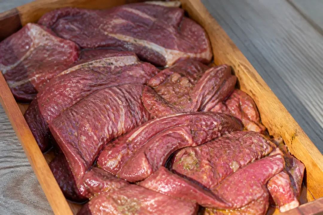 Tranches de viande pour carbonnade fraîchement découpées dans un plateau en bois rustique